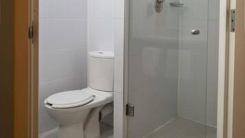 A bathroom with a toilet, a glass shower enclosure, and a tiled floor.