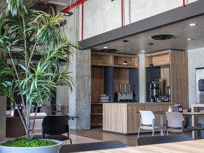 A modern cafe with a bar area, seating, and a large potted plant. - ibis Hermosillo (Hermosillo)