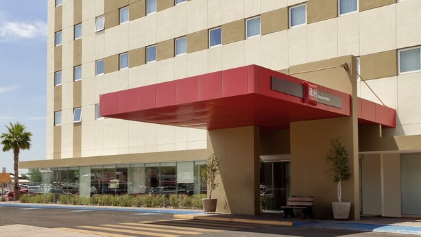 A hotel with a modern facade, multiple floors, and a prominent red awning. - ibis Hermosillo (Hermosillo)