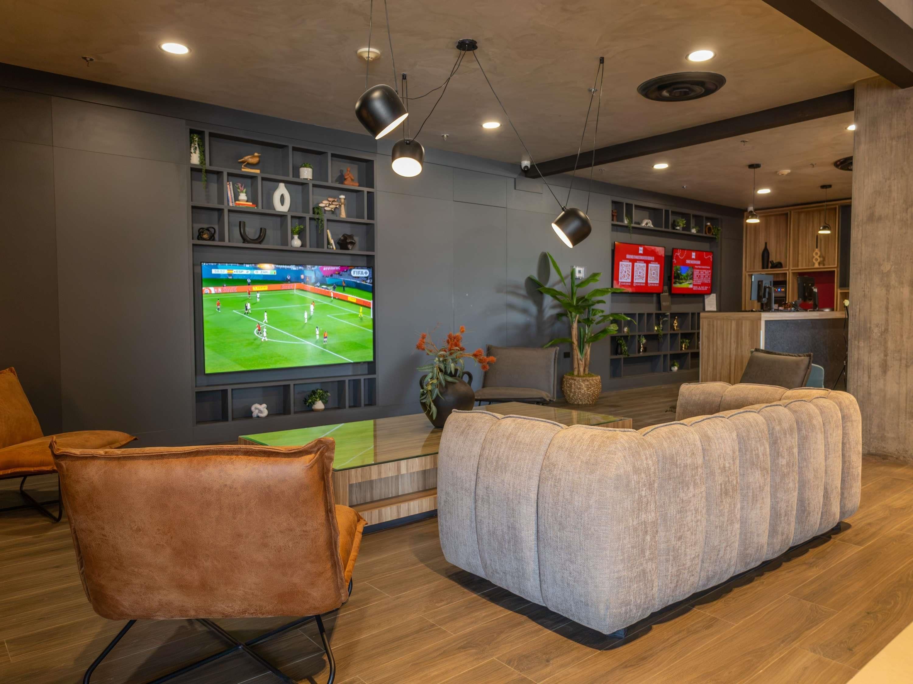 Una sala moderna con un televisor de pantalla plana grande, un sofá cómodo, un sillón de cuero y una mesa de centro.
