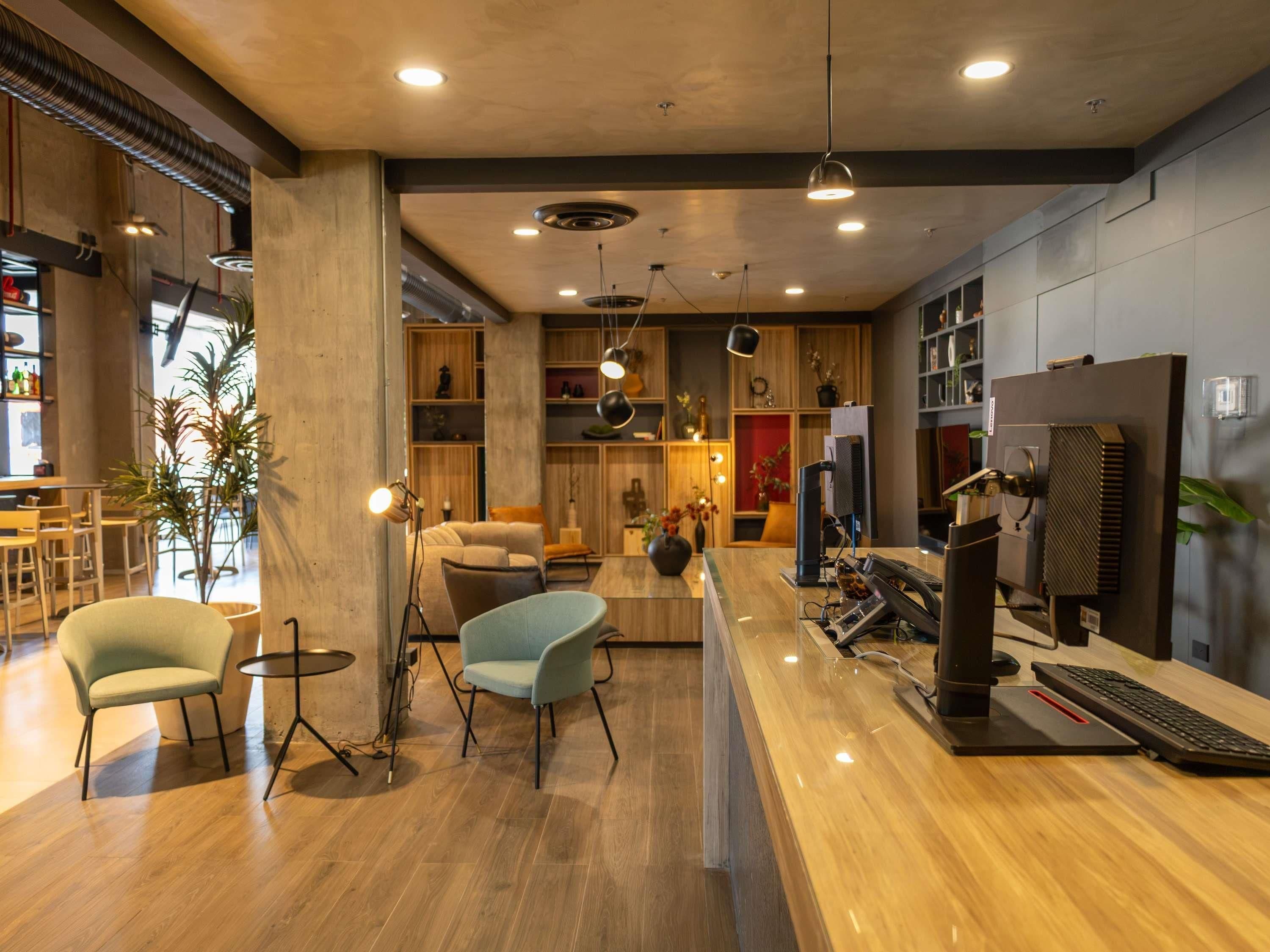 Un interior moderno con un mostrador de recepción de madera, zona de estar y bar.