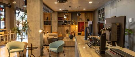 Un interior moderno con un mostrador de recepción de madera, zona de estar y bar.