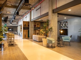 A spacious indoor area with a long wooden floor, seating arrangements, and a large plant.