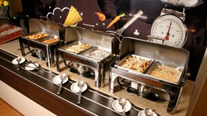 A buffet setup with multiple serving stations, each with a variety of dishes. - ibis Hermosillo (Hermosillo)