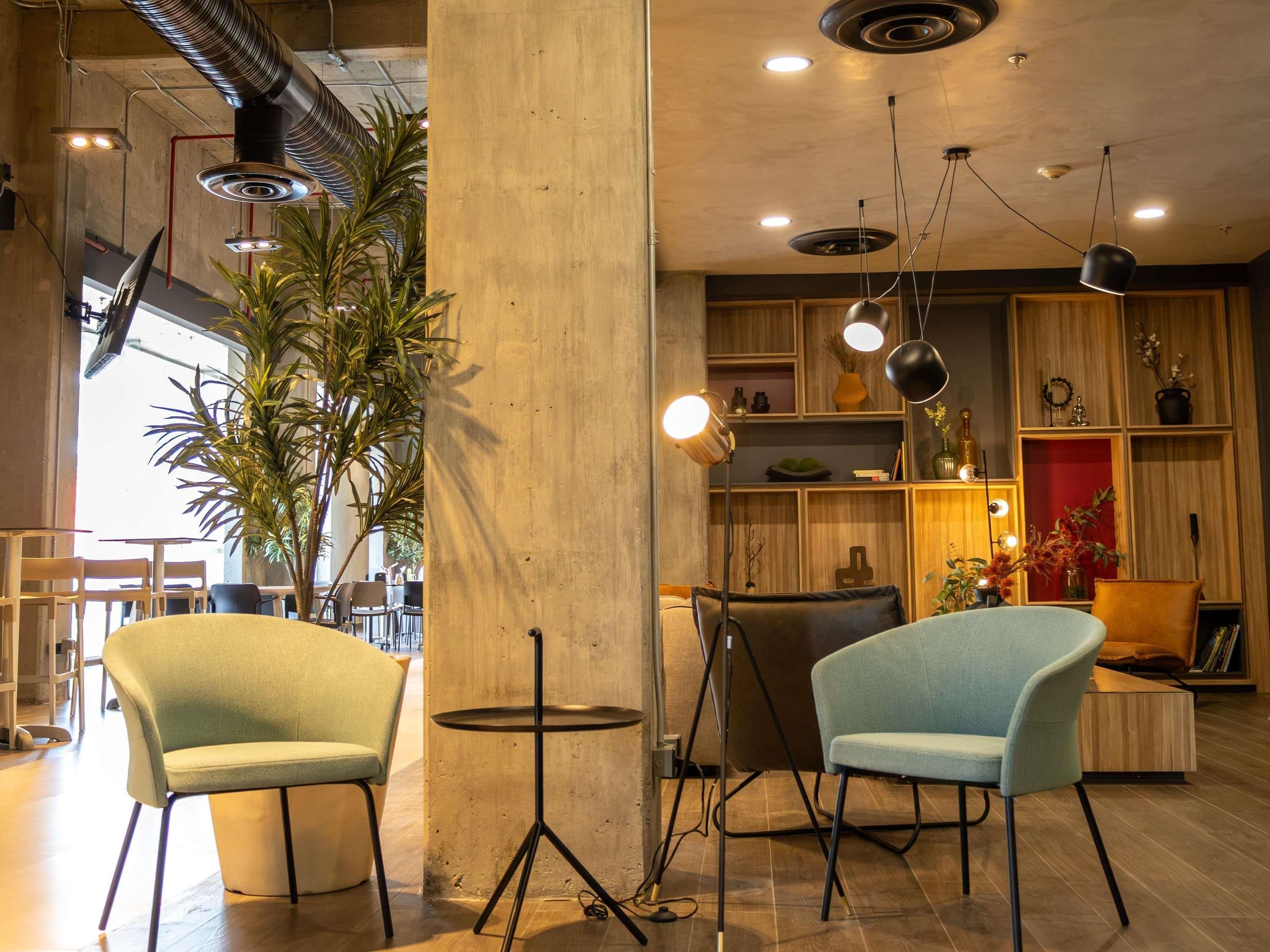 A modern interior with two chairs, a round table, and a bookshelf.
