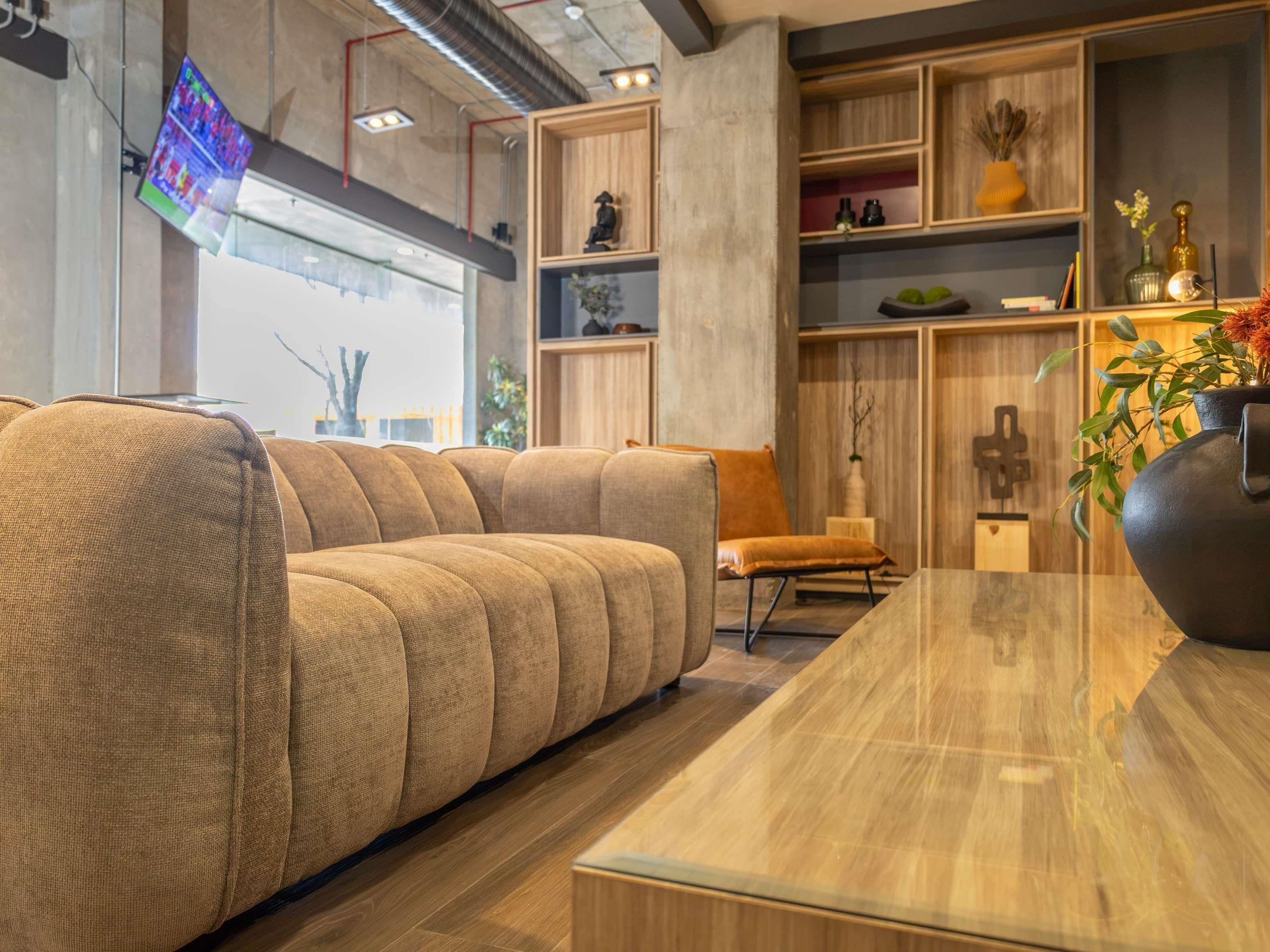 A modern living room with a sectional sofa, wooden shelving, and a large vase with flowers.