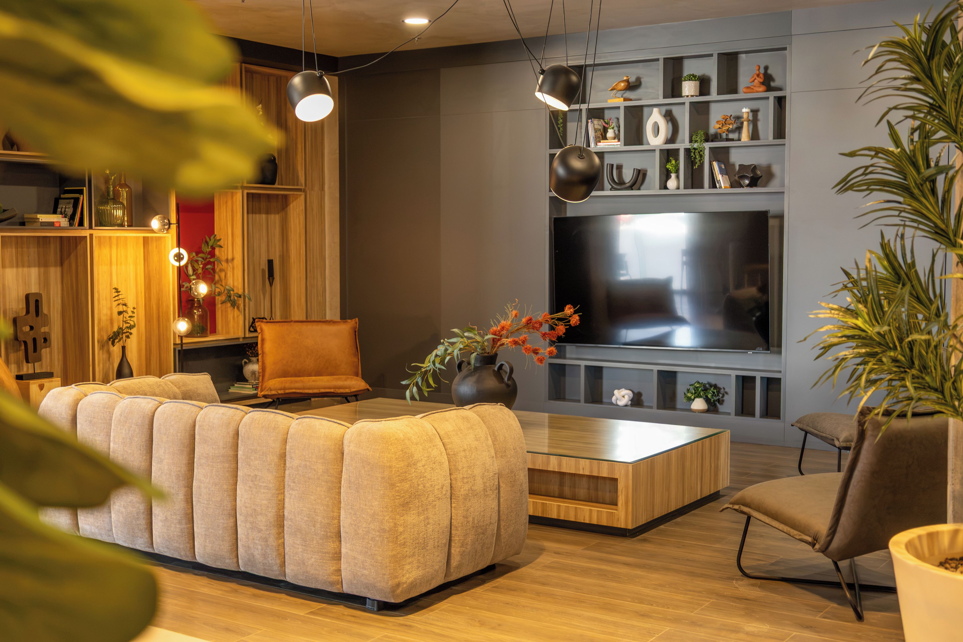 Una sala moderna con un sofá modular, una mesa de centro, un televisor y varios objetos decorativos.