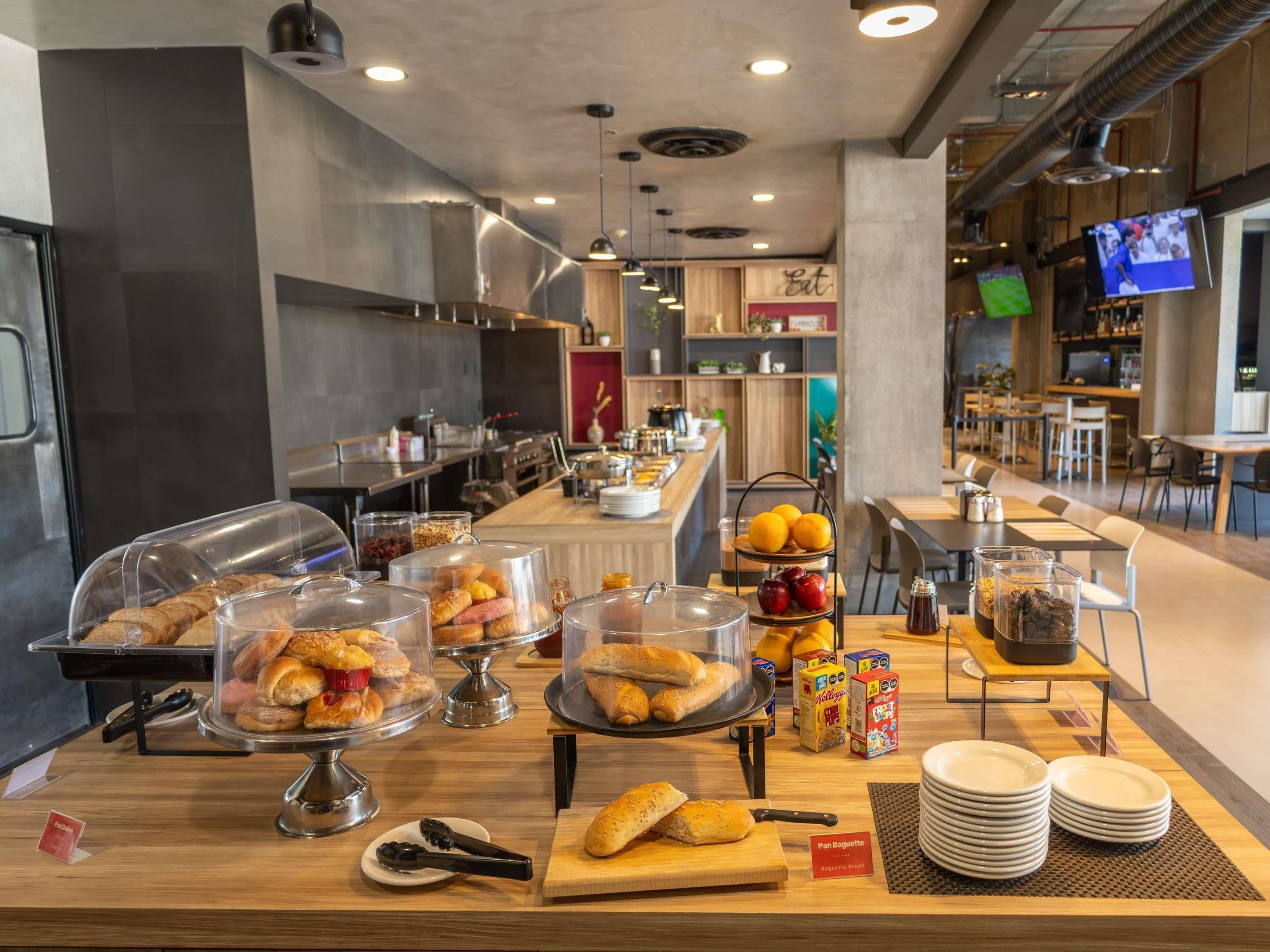 A breakfast buffet with various pastries and bread, a coffee station, and a seating area with tables and chairs.