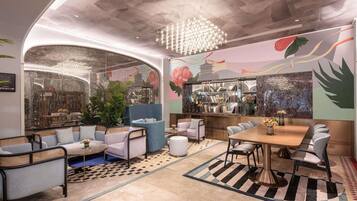 A modern interior with a curved ceiling, a chandelier, a seating area with sofas and chairs, a bar with bookshelves, and a mural on the wall.