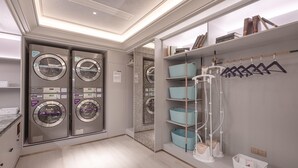 A laundry room with four washing machines, a drying rack, and a shelving unit with hanging clothes. - Mercure Xi'an High-tech Zone Center (Xi'an)