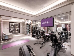 A gym with exercise equipment, a purple sign, and a mirror reflecting the room. - Mercure Xi'an High-tech Zone Center (Xi'an)