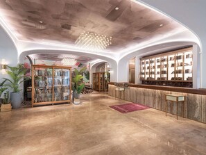 A lobby with a reception desk, a glass display case, and a chandelier.
