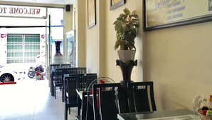 A restaurant interior with tables and chairs, a potted plant, and a menu on the wall. - Canary Hotel Hue (Hue)