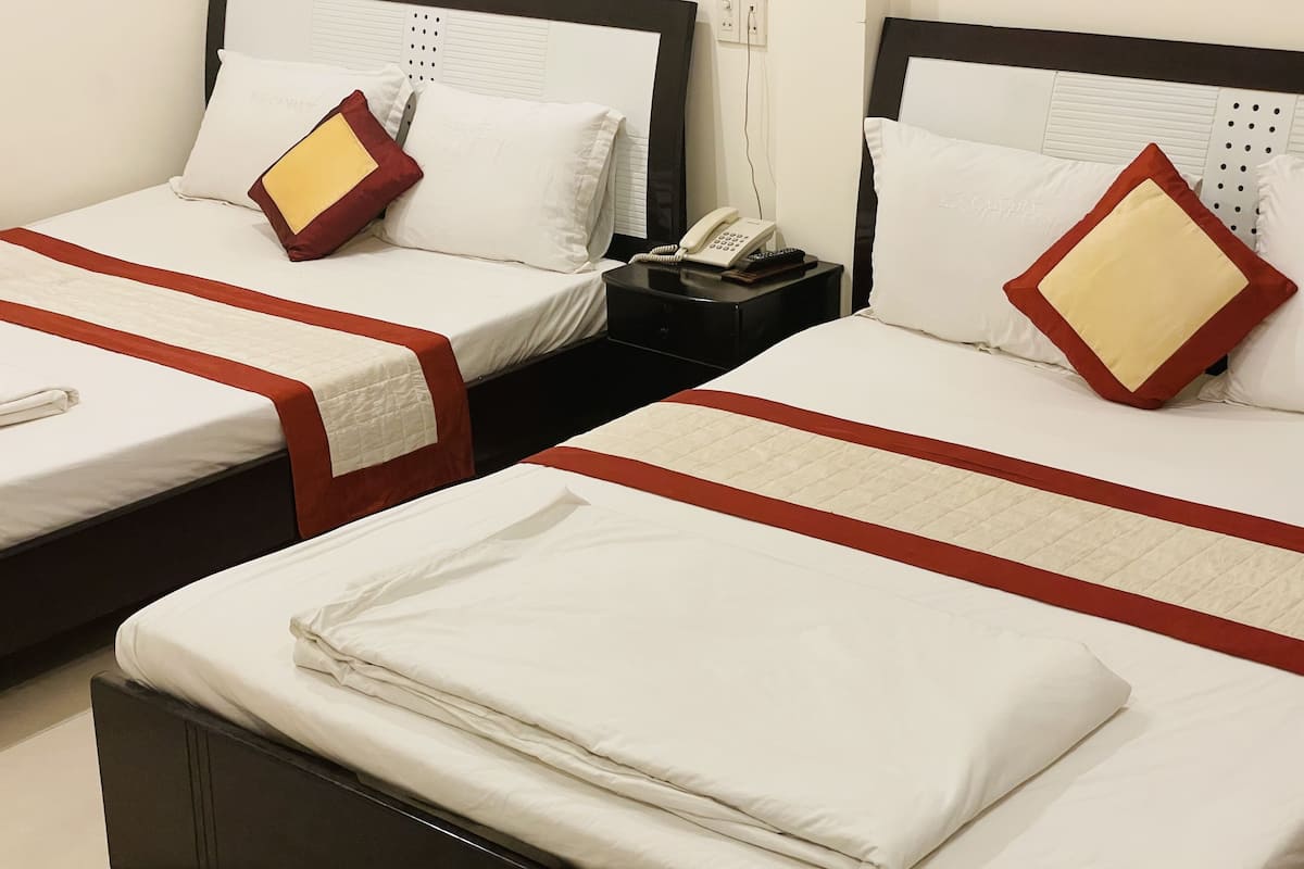 A hotel room with two beds, each with a red and white bedspread, a telephone, and a nightstand.