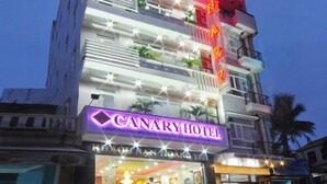A multi-story hotel with a prominent neon sign for "CANARY HOTEL" and balconies with plants. - Canary Hotel Hue (Hue)