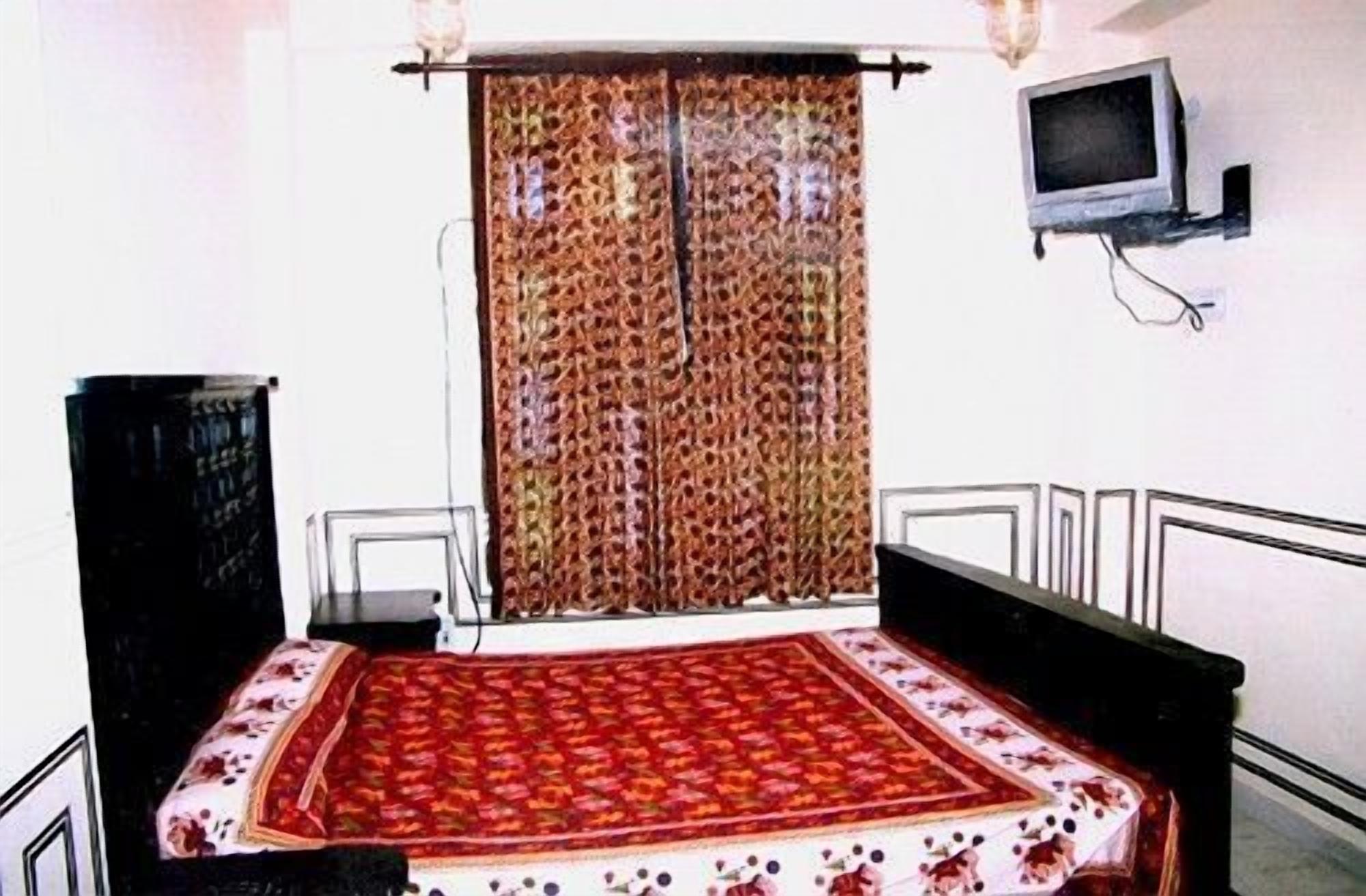 Un dormitorio con una cama, un televisor en la pared y una cortina.