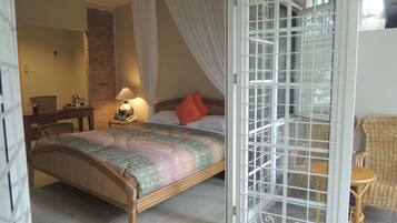 A bedroom with a bed, a nightstand, a lamp, a chair, and a window with a metal screen.