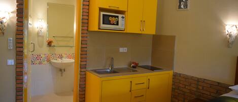 A compact room with a yellow kitchenette, a sink, and a microwave.