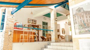 A staircase leading to a room with a wooden ceiling, a brick wall, and a window with blinds. - Hotel Deli River (Medan)