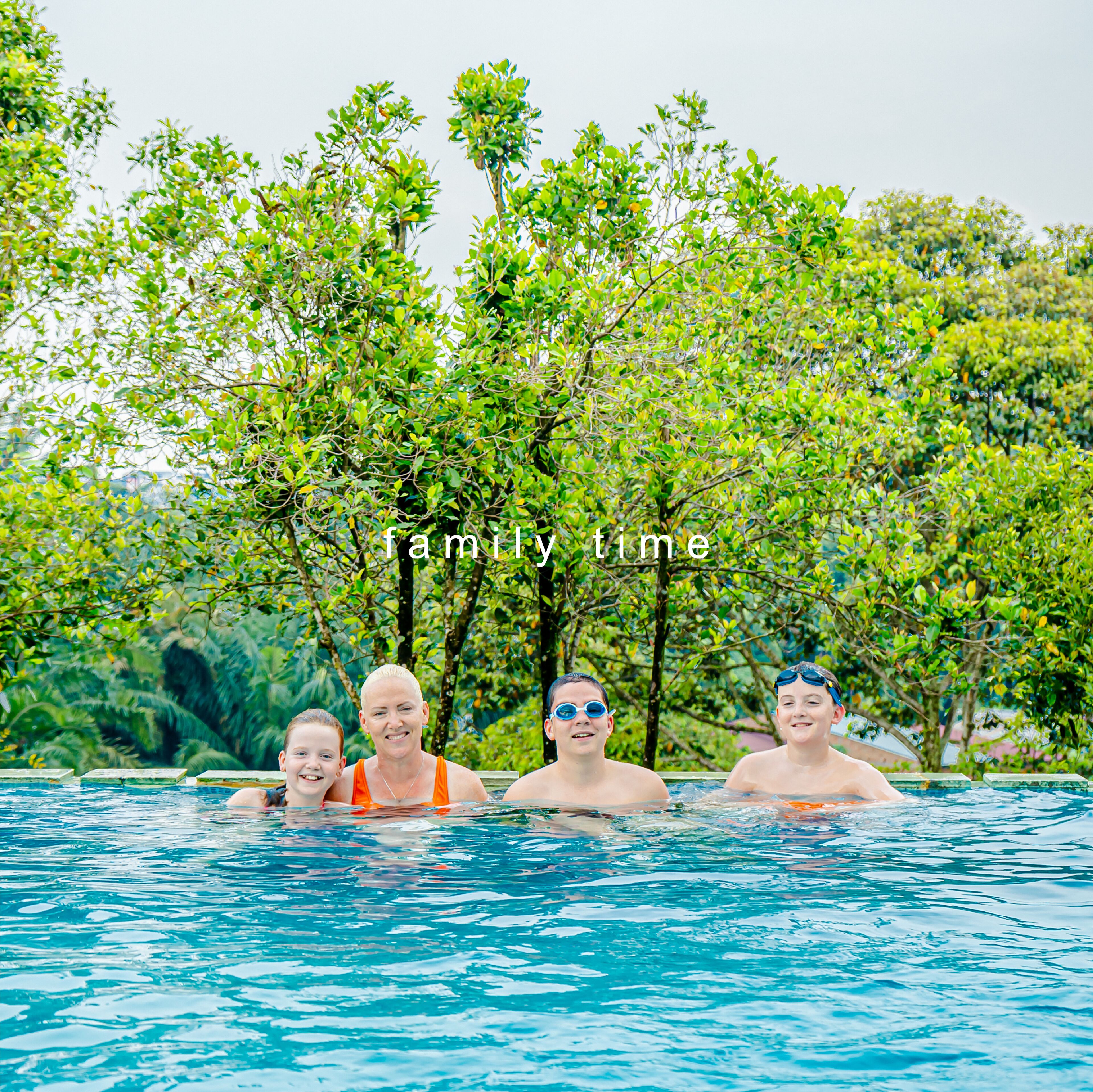 A family in a swimming pool surrounded by lush greenery.