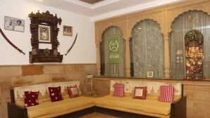 Una habitación tradicional con sofá, espejo decorativo e imágenes enmarcadas en la pared.