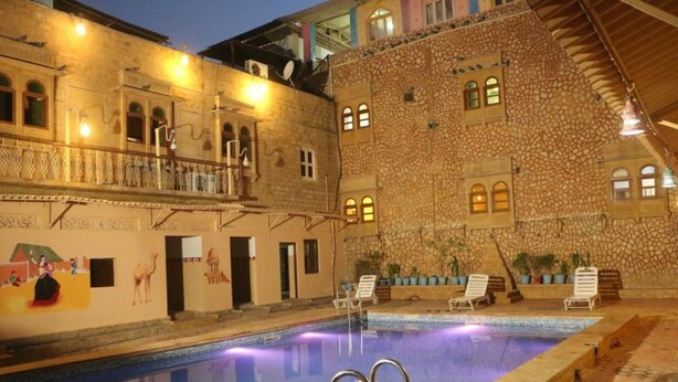 Una piscina interior con paredes de piedra y un balcón con vistas a la zona de la piscina.
