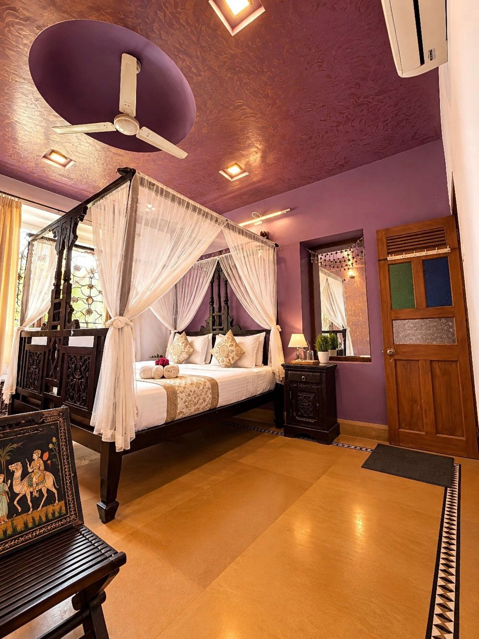 A four-poster canopy bed with a wooden frame, white bedding, and decorative pillows.