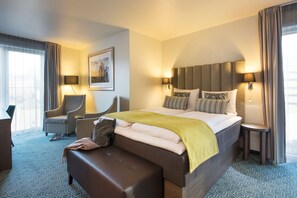 A hotel room with a large bed, a sofa, a chair, and a small table. - Scandic Bakklandet (Trondheim)