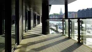 A corridor with large windows overlooking a parking area and buildings.