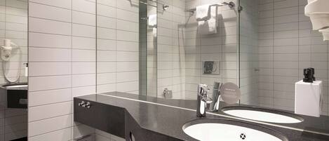 Un baño moderno con dos lavamanos, un espejo grande y cabina de ducha de cristal.