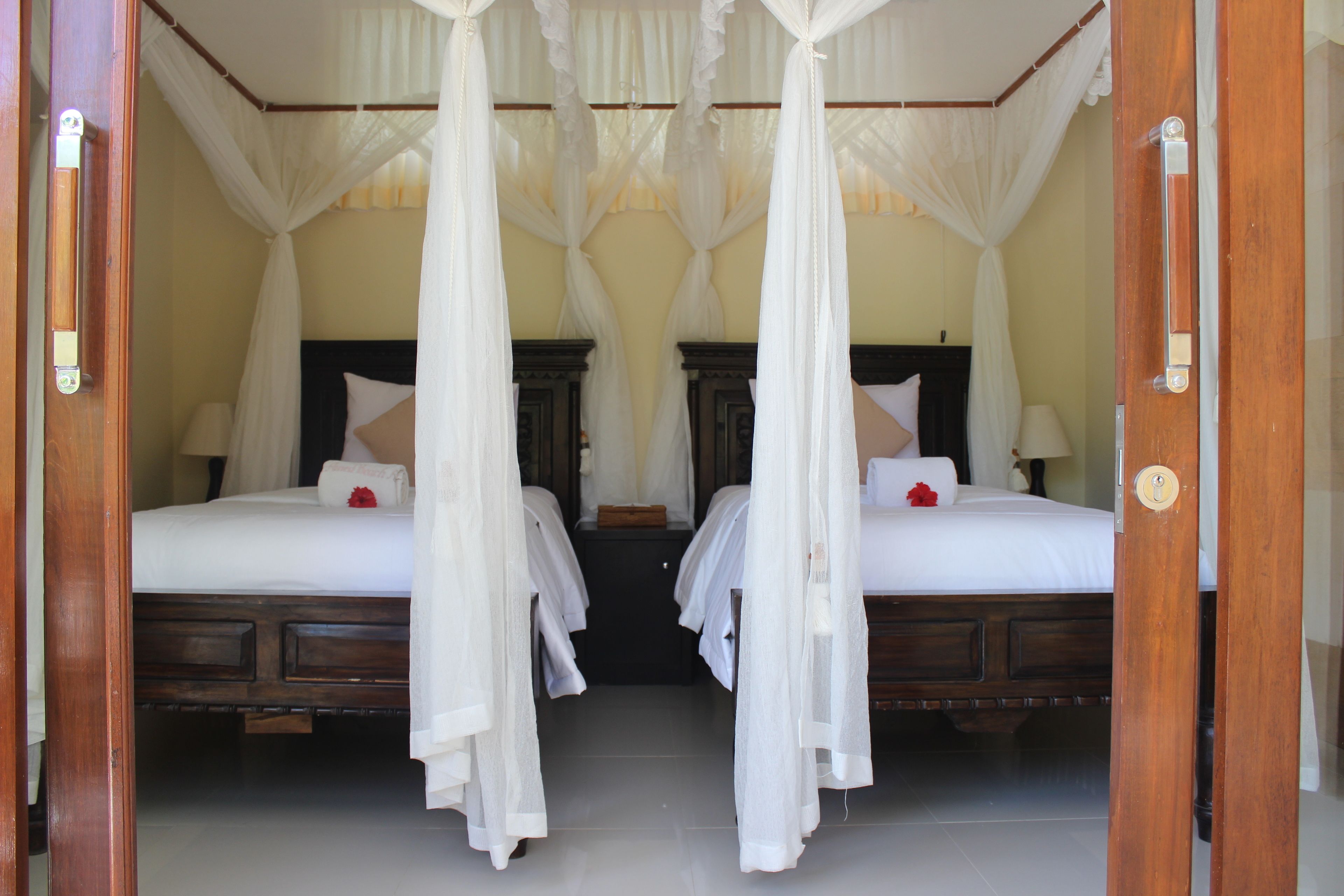 A room with two beds, each with a canopy bedspread and pillows.