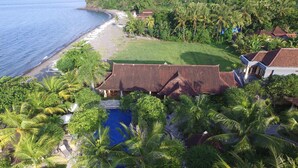 A resort with a swimming pool, a beach, and lush greenery.