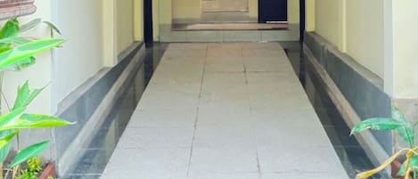 A corridor with a tiled floor, a central rug, and a small garden area with plants.