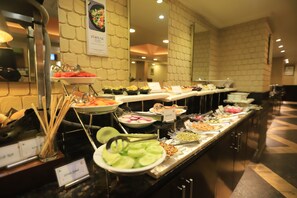 Enjoy a wide selection of international cuisine at our buffet, featuring sliced meats, fresh produce, and a variety of prepared dishes.