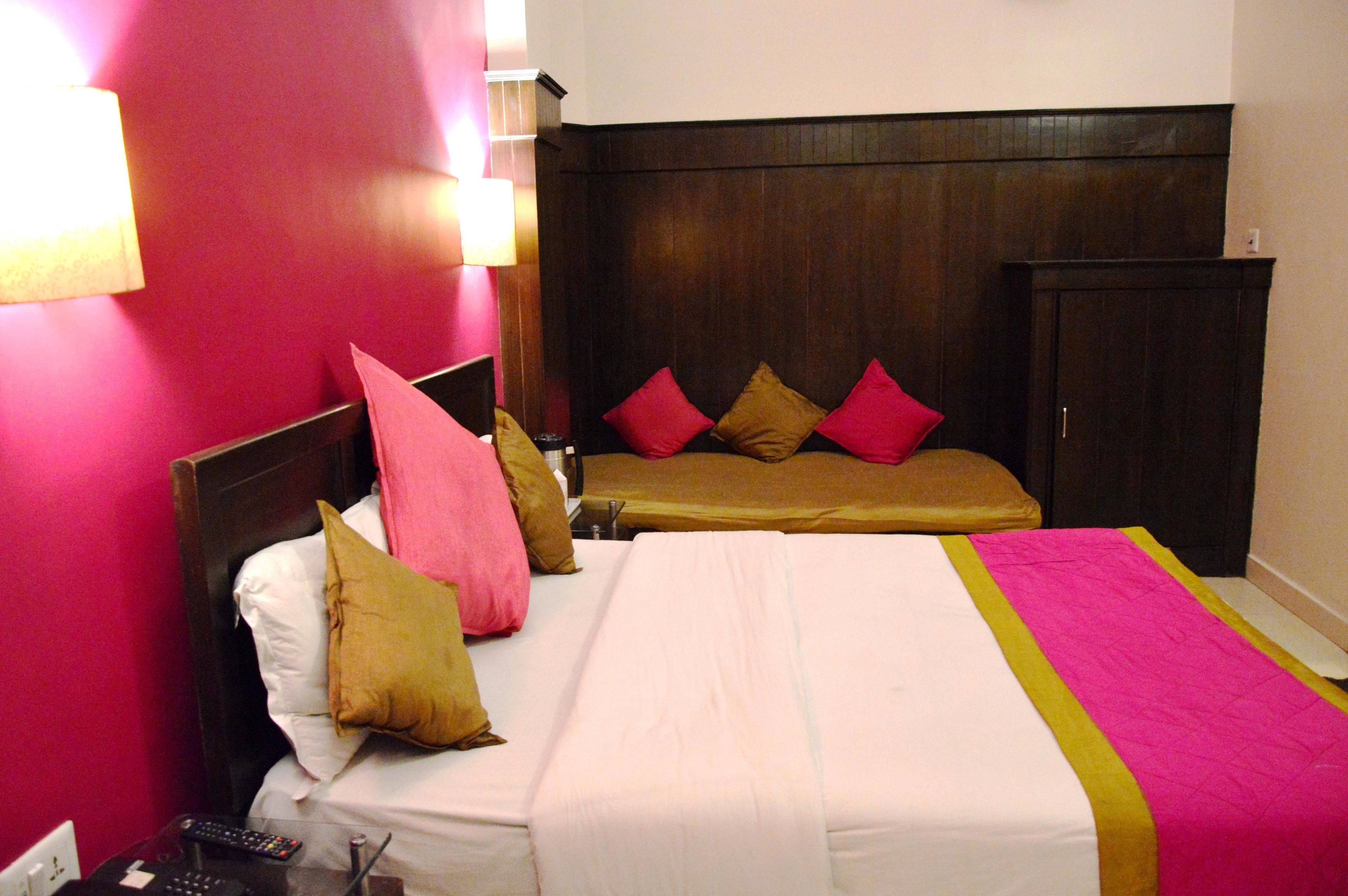 Una habitación de hotel con una cama grande, cabecera de madera y pared rosa.