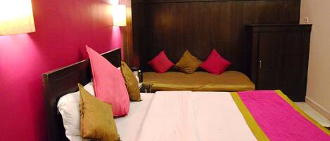 Una habitación de hotel con una cama grande, cabecera de madera y pared rosa.