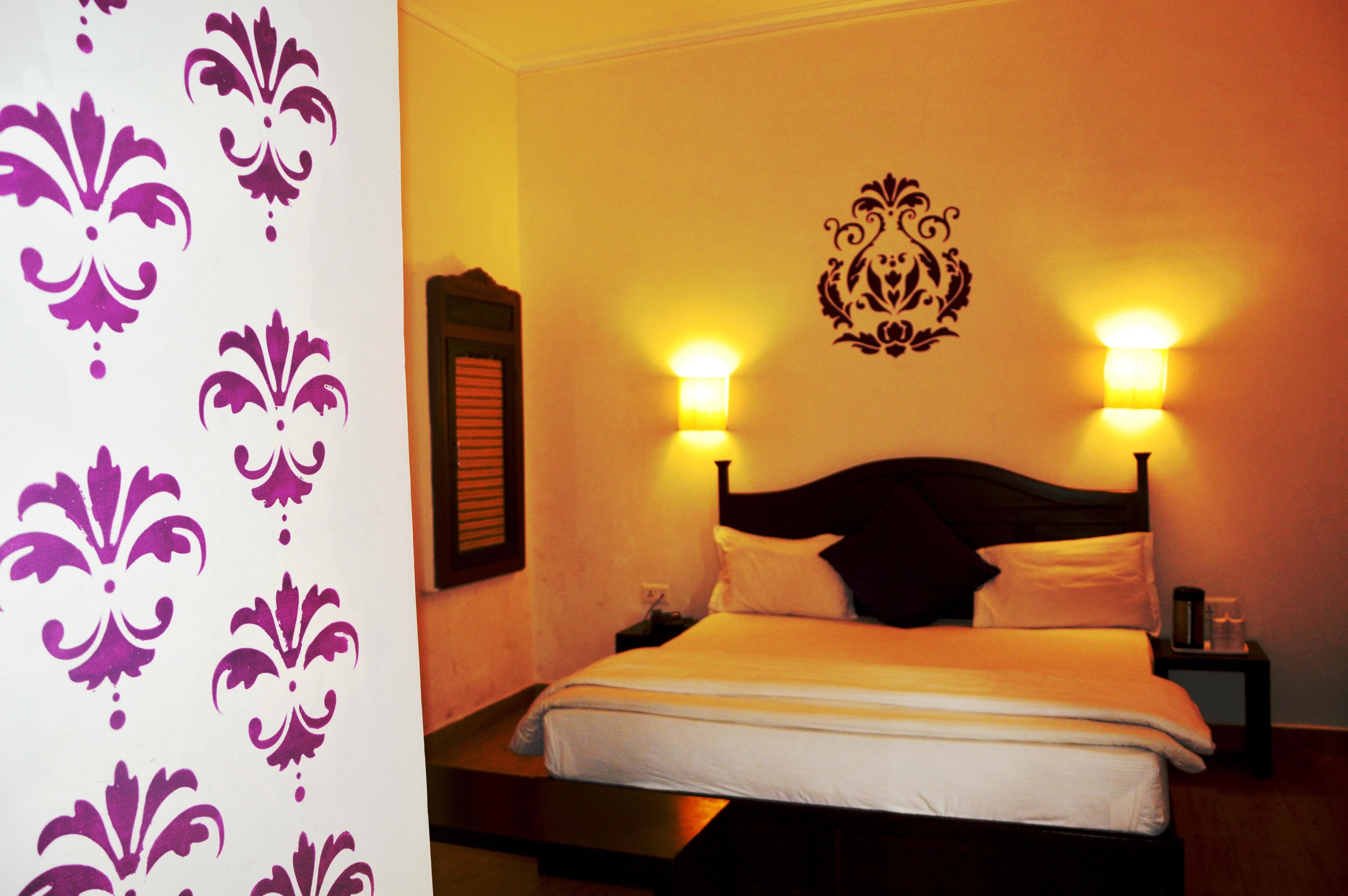 A neatly made bed with white linens, two bedside lamps, and a decorative wall piece above the bed.