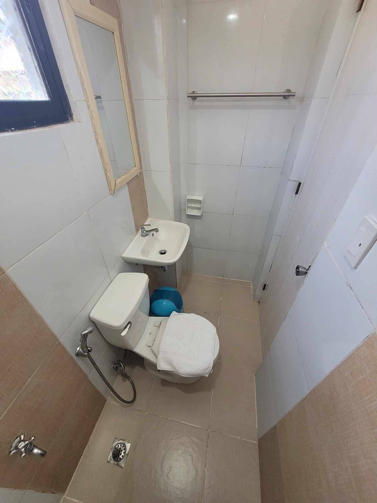 A small bathroom with a toilet, sink, and shower.
