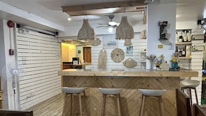 A bar area with wooden stools, a counter, and hanging light fixtures.