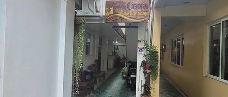 A narrow alleyway with a sign for 'La Casa de Boracay' above a doorway. There are potted plants along the sides and a fire hydrant in the center.