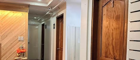 Un pasillo con puertas de madera, un muro de madera y una pequeña mesa con una estatua.