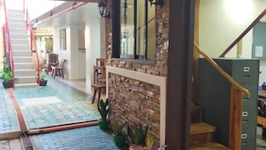 A staircase leading to a landing with a wooden railing, a brick floor, and potted plants.