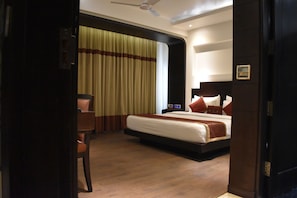 A hotel room with a bed, a desk, and a chair. - Hotel Godwin Deluxe Near New Delhi Railway Station (New Delhi)