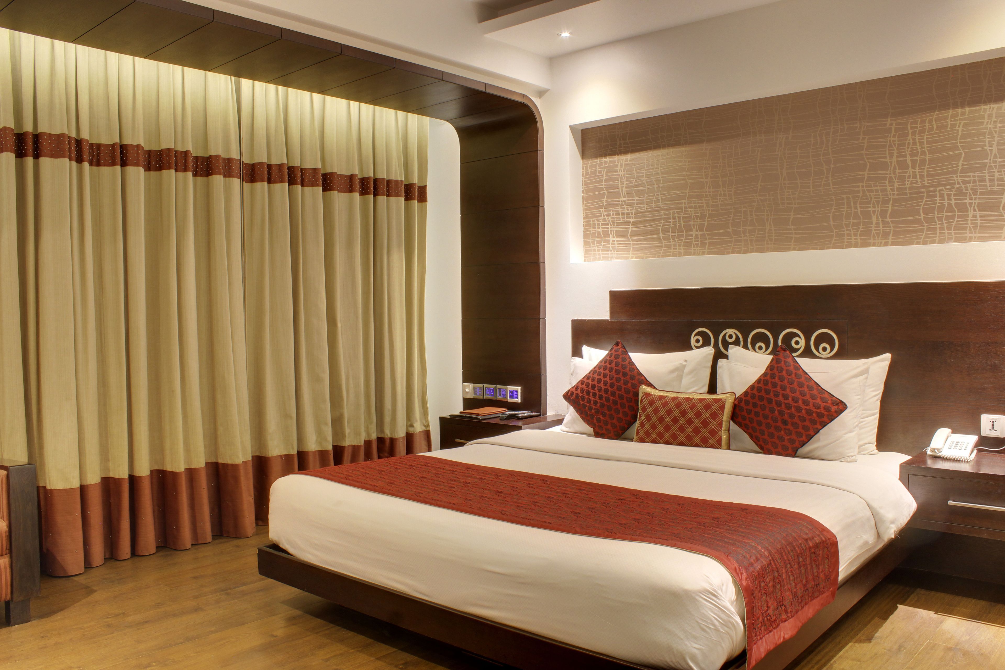 A hotel room with a large bed, a nightstand with a phone, and a wall-mounted artwork.