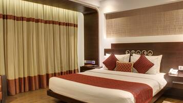 A hotel room with a large bed, a nightstand with a phone, and a wall-mounted artwork.