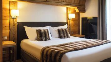 Une chambre d’hôtel avec un grand lit, une tête de lit en bois, deux tables de chevet et des lampes fixées au mur.