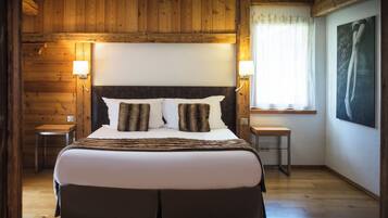 Une chambre à coucher avec un grand lit, des murs en bois, une fenêtre avec des rideaux et un tableau accroché au mur.
