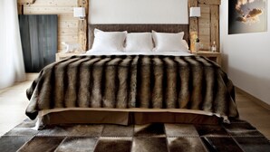 Una cama con un plaid de piel sintética, cabecera de madera y un cuadro de nubes en la pared.