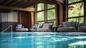 Una piscina interior con sillones reclinables y ventanas amplias.