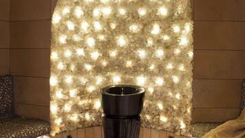 A spa area with a stone ceiling, a wall of illuminated lights, and a black vase in the center.